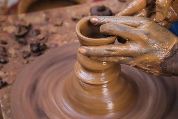 istock Dirty Hands Of Potter Making Pottery From Mud Using Spinning Potter Wheel 1278634108