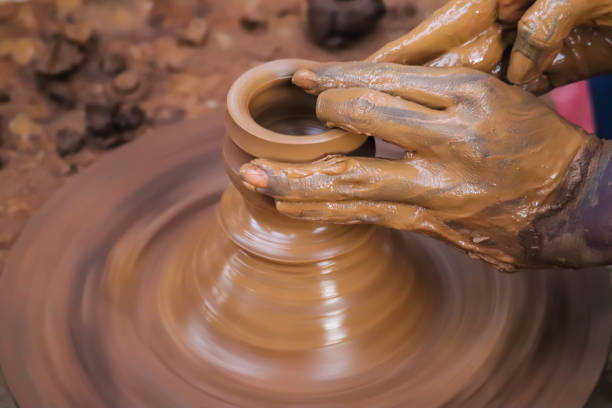 istock Dirty Hands Of Potter Making Pottery From Mud Using Spinning Potter Wheel 1278634143