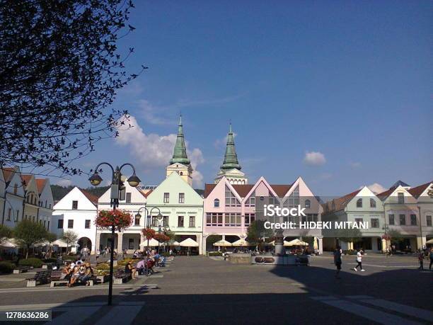 Sunny Blue Sky Old Town Cobbled Square Colorful Building Facades With A Fountain And A Tree Branches Silhouette Stock Photo - Download Image Now