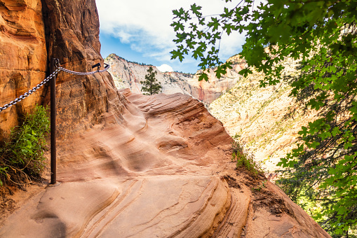 A footpath with a metal chain for added safety on a mountain in Zion National Park, USA.