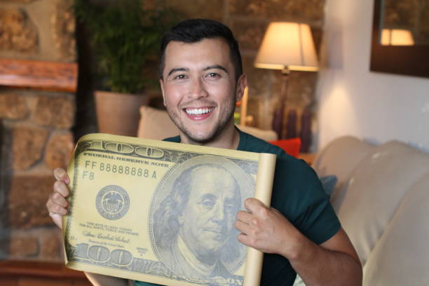 istock Young ethnic man holding gigantic 100 dollars bill 1278645089