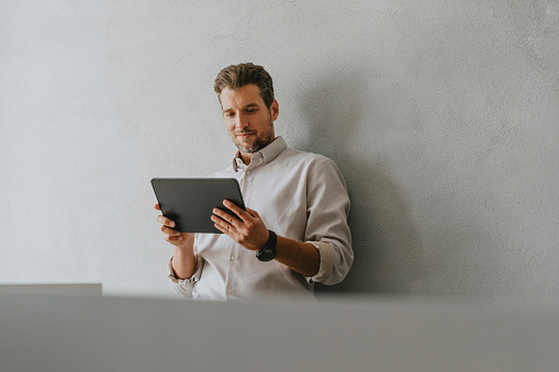 Staying connected in the office: a handsome businessman using his digital tablet at work.