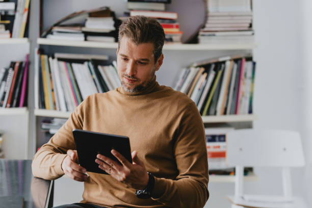 istock Handsome Freelance Businessman Using a Digital Tablet in his Office/ Library 1278645170