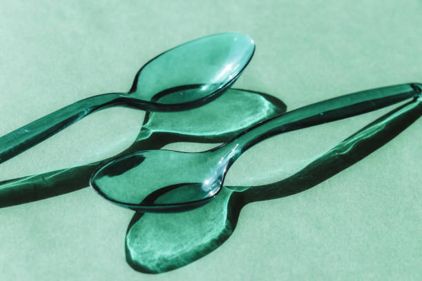 istock Two green transparent plastic spoons with contrasting shadows 1278646711