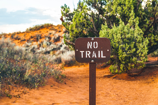A wooden no trail sign inside the desert of the Arches National Park in Utah, United States.