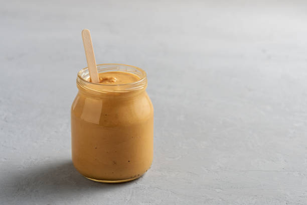 istock Homemade peanut butter in a glass jar on a concrete surface. 1278655031