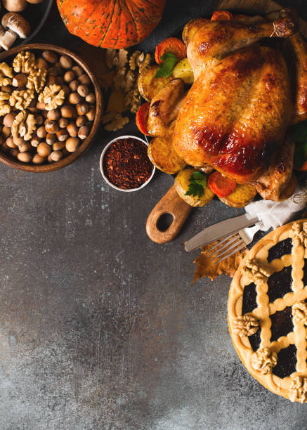 istock Fall thanksgiving table with roasting chicken or turkey, nuts, pie, pumkins and other food on dark background 1278655452
