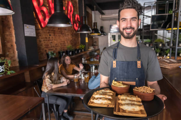 a smiling hispanic waiter is holding a tray of empanadas - 7595 imagens e fotografias de stock