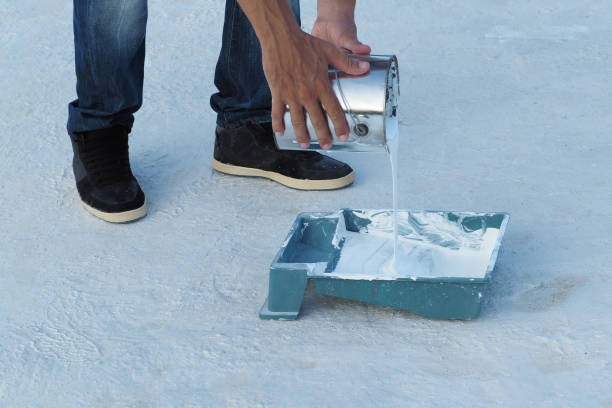 istock Man pouring white waterproof paint from bucket in container at roof. 1278658164