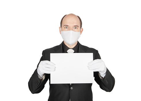 Handsome young business man with surgical medical virus protection white mask and gloves holding empty sheet of paper isolated