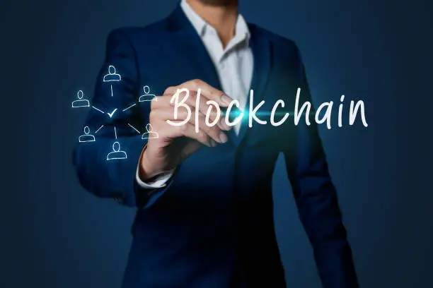 Blockchain concept business man hand writing with the word blockchain with icon