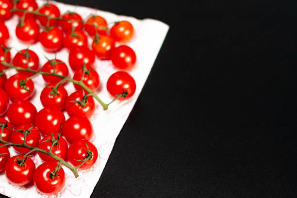 Clusters of cherry tomatoes on a white surface. There's an empty seat on the right. Dark background.