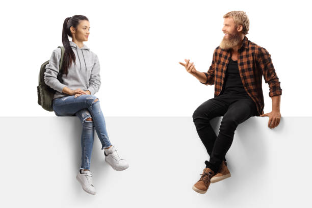 istock Bearded guy sitting on a white panel and talking to a female student 1278664224