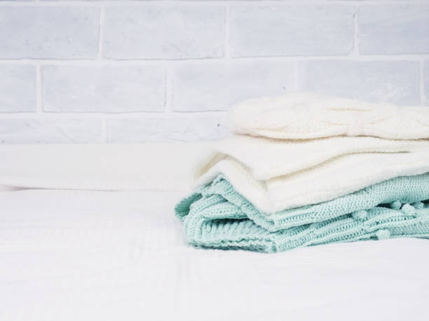 istock A stack of warm knitted things on a white bed. Cozy clothes. Household concept. folded knitted things white 1278665870