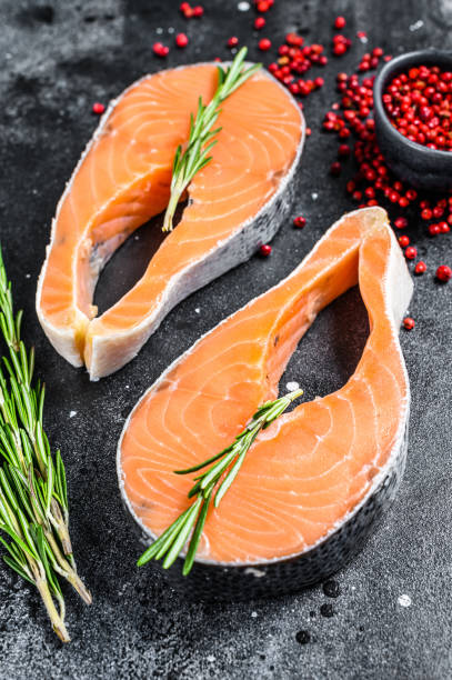 istock Two fresh raw salmon steaks with pepper and rosemary. Black background. Top view 1278668352