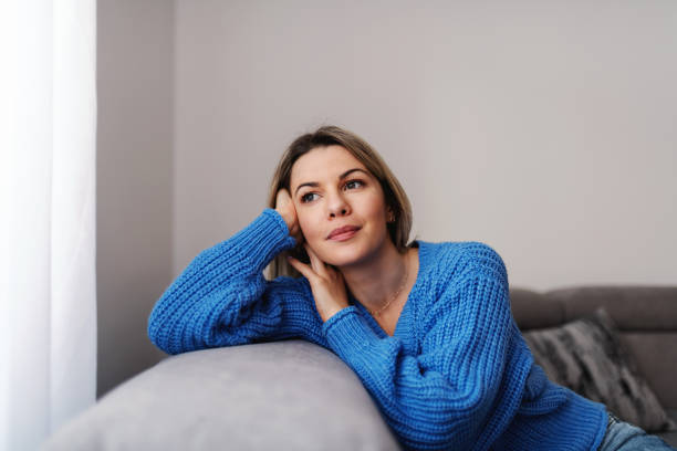 istock Young attractive thoughtful blonde woman leaning on sofa and looking trough window during corona outbreak. 1278668575
