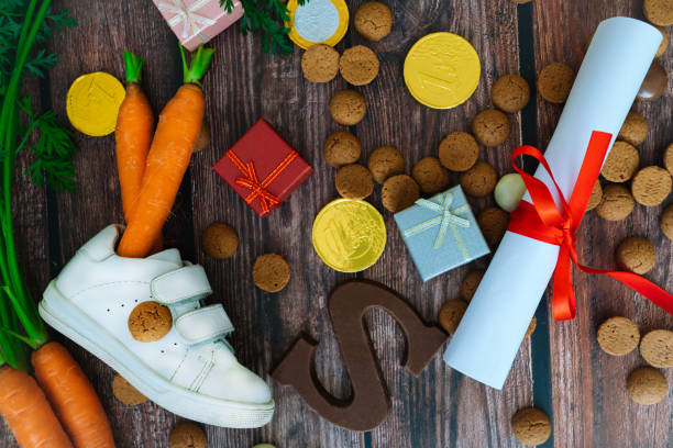子供靴、サンタの馬のためのニンジン、贈り物、伝統的なお菓子ペペルノテンとチョコレートの手紙とオランダの休日シンタークラースの背景。コピースペース付きフラットレイ。 - dutch sinterklaas ストックフォトと画像