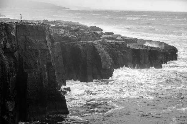 schwarze und weiße meereslandschaft irischer klippen, die von wellen heimgesucht werden, irland - republic of ireland cliffs of moher cliff galway stock-fotos und bilder