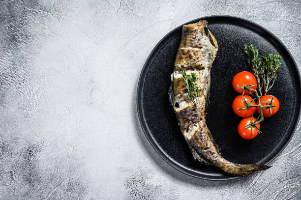 istock Delicious grilled hake with fresh thyme and tomatoes. Black background. Top view. Copy space 1278669903