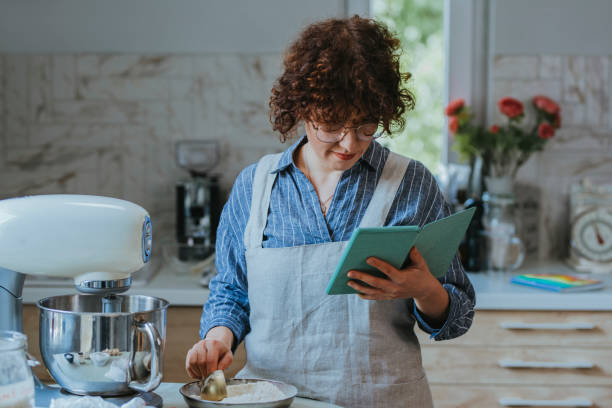 istock Home Baker: a Woman Wearing an Apron Reading a Recipe on her Digital Tablet 1278671177