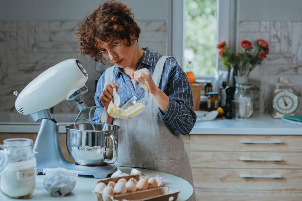 istock Baking at Home: a Young Woman in an Apron Adding Butter into the Mixing Bowl 1278671185