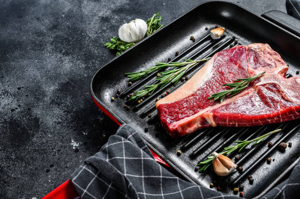 istock T bone steak in a pan. Organic raw Tbon beef. Black background. Top view. Copy space 1278671253
