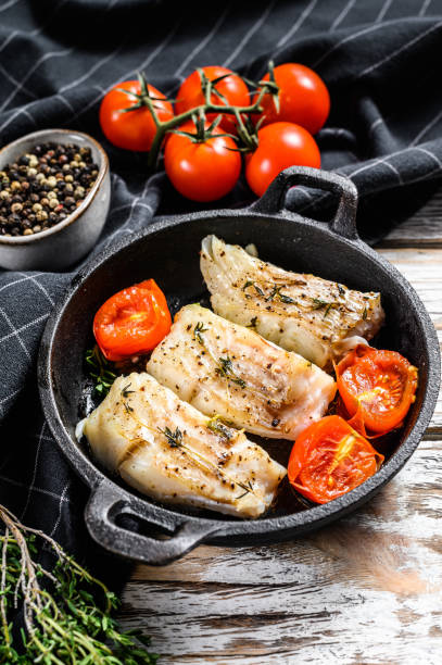 istock Fried cod fish fillet with spice in a cast iron pan.  White background. Top view. 1278673305
