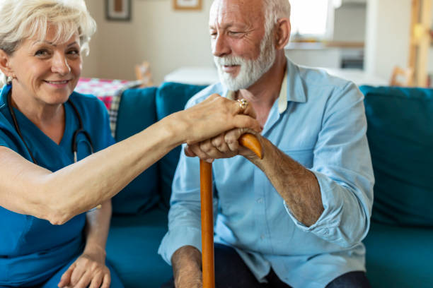 istock Friendly mature general practitioner communicating with pleasant 70s male patient, sitting together on sofa. Smiling trustful middle aged doctor giving psychological help to elder man at home visit. 1278673378