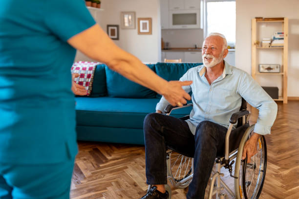 istock Physical disability. Nice sad aged man holding a caregivers hand and trying to get up while having a physical disability 1278674199