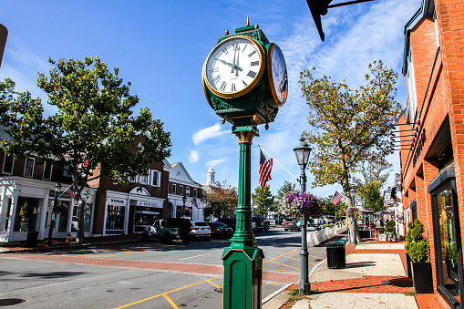 New Canaan, CT, USA - October 4, 2020: Downtown in nice day with clock, store fronts, restaurant and blue sky on Elm Street
