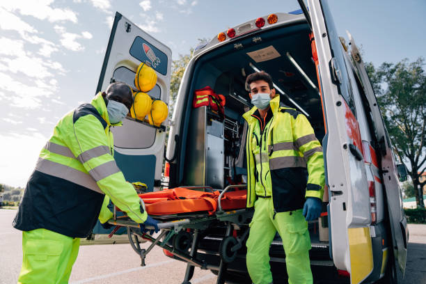 Two paramedics with a stretcher near an ambulance Two paramedics with a stretcher near an ambulance. They are wearing protective face masks. frontline worker mask stock pictures, royalty-free photos & images