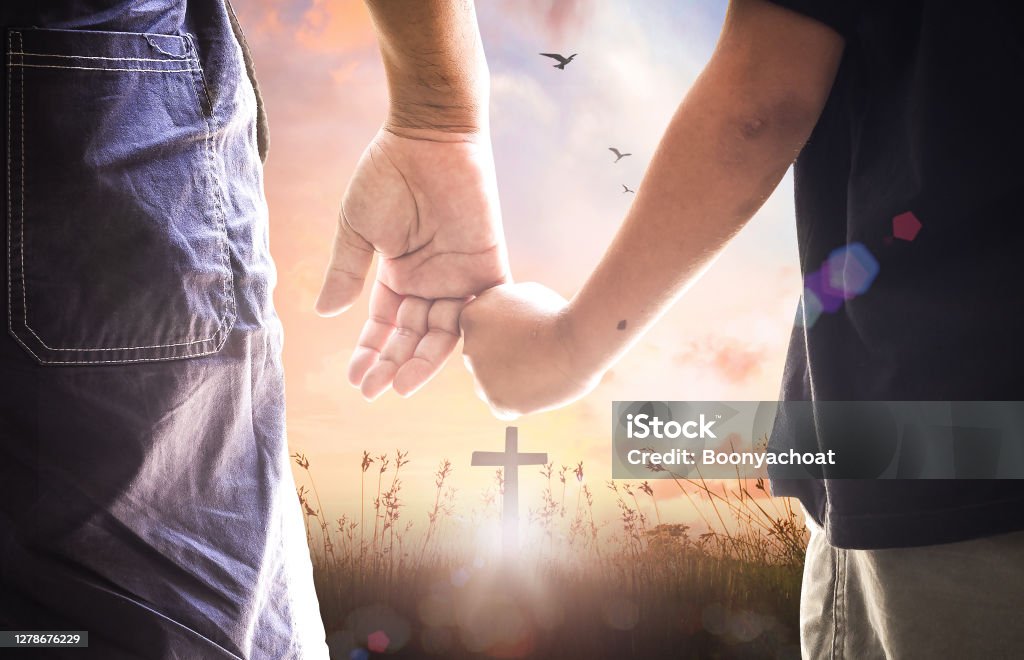 Worship God concept Father and son hold hands and stand in front of the cross Praying Stock Photo