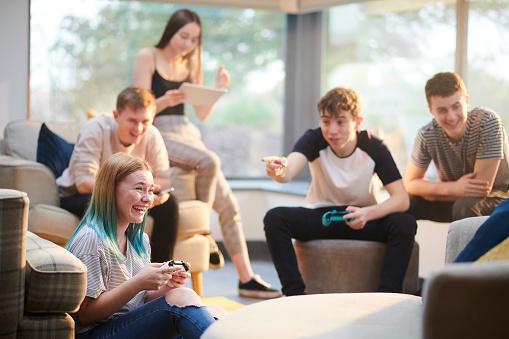 a group of teenage friends play video games in a living room
