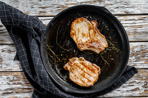 Grilled pork cutlets in a pan.  Organic meat steak. White background. Top view.