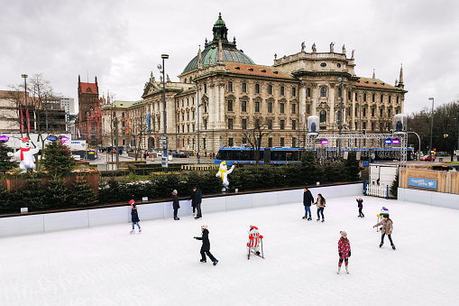 Munich, Germany - Jan 4th 2020: People have fun ice skating on an artificial ice rink on Karlsplatz (Stachus) in Munich, Germany