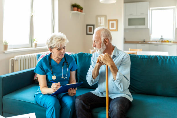 Mature volunteer visiting elder man in need Nurse checking on patient .Smiling man looking at female nurse working seniors stock pictures, royalty-free photos & images