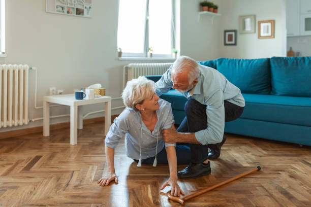 femme âgée handicapée a eu un malheur et est tombé sur le plancher en bois dans le salon de son appartement. - falling people tripping senior adult photos et images de collection