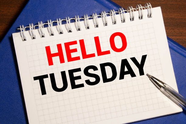 istock HELLO TUESDAY written in red on a light background near a computer, a pen. 1278688297