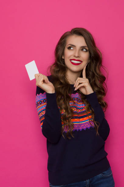 istock Young Woman In Sweater With Colorful Pattern Holds White Card And Thinking 1278695583