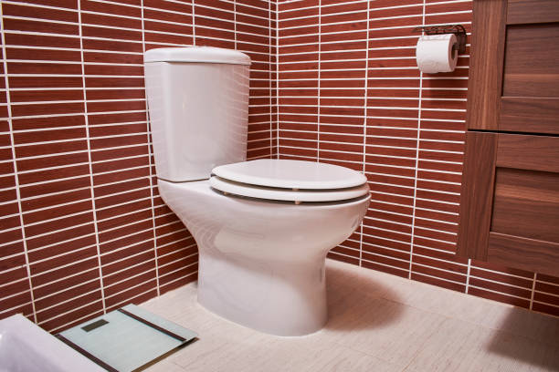 istock Glossy white toilet installed in a modern bathroom in brown and white tones 1278704214