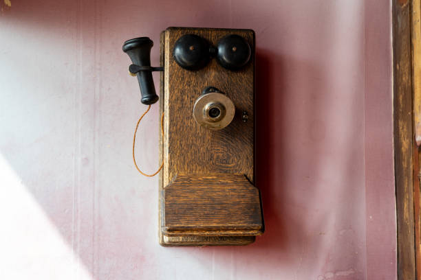 istock Old fashioned telephone earphone from the 1900s, on a wall. Pink background 1278707075