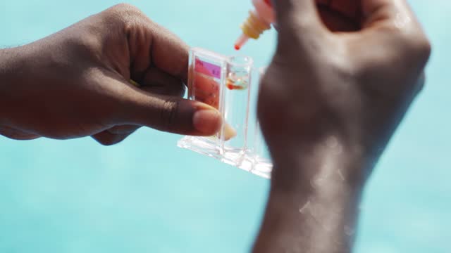 asian indian lifeguard Pool testing kit being used in a swimming pool for water chlorine and ph  level