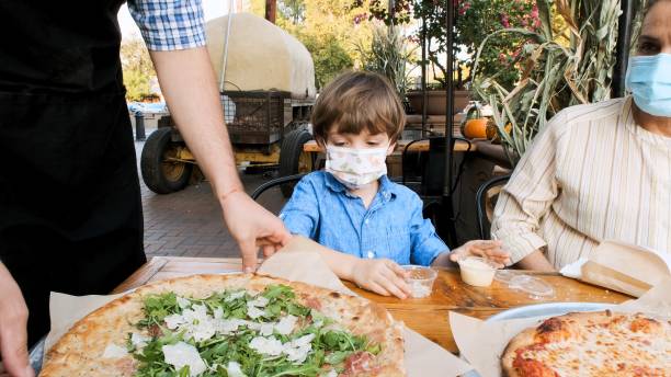 istock Mother and son having pizza outdoors wearing protective face masks 1278708752