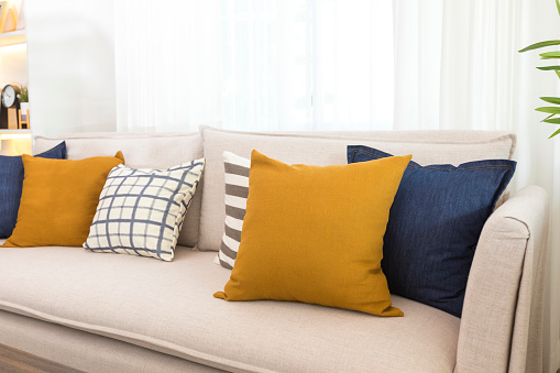 Blue and yellow pillows on a white sofa, living room interior