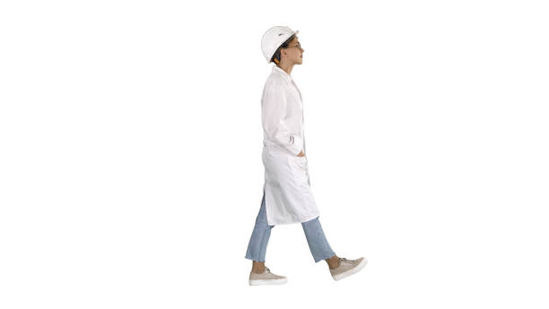Walking woman engineer with hands in pockets on white background