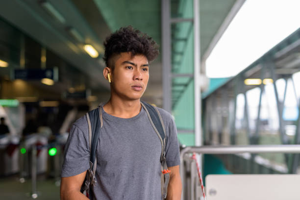 istock Young Asian tourist man as backpacker thinking at the sky train station 1278712425