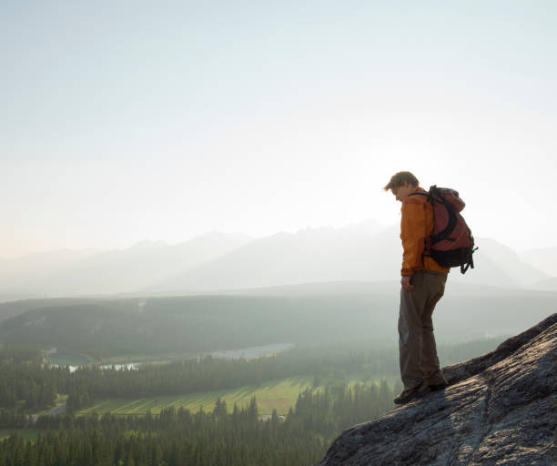 istock Backpacker stands on edge of cliff above valley 1278733967
