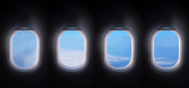 four airplane windows open white window shutter wide with blue sky view. plane portholes usable for banners, brochures in tourism theme. traveling by air concept