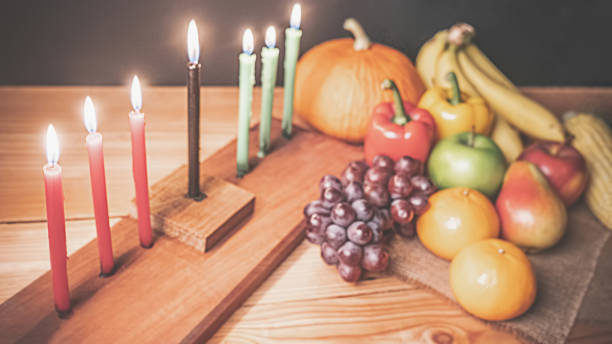 Kwanzaa holiday concept with decorate seven candles red, black and green, gift box, pumpkin,corn and fruit on wooden desk and black background. Kwanzaa holiday concept with decorate seven candles red, black and green, gift box, pumpkin,corn and fruit on wooden desk and black background. angolan kwanza photos stock pictures, royalty-free photos & images