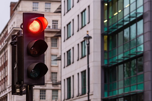 Red traffic lights for cars on a blurred buildings background - image
